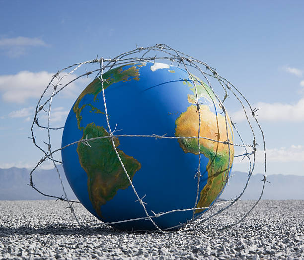 un globe entangled de fil barbelé - barbed wire fence wire danger photos et images de collection