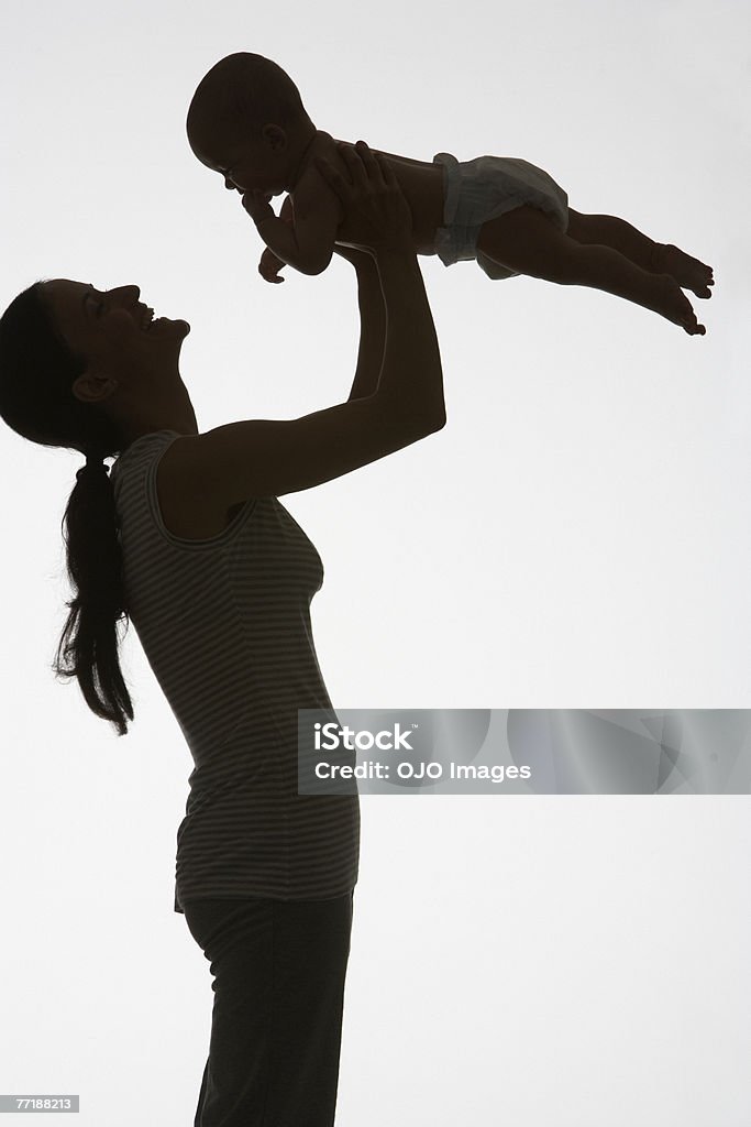 A woman playing with a baby  In Silhouette Stock Photo