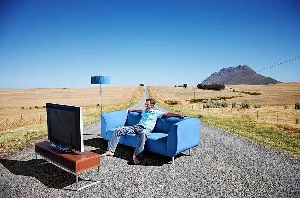 un homme regardant la télévision sur un canapé à la route - rural watch photos et images de collection