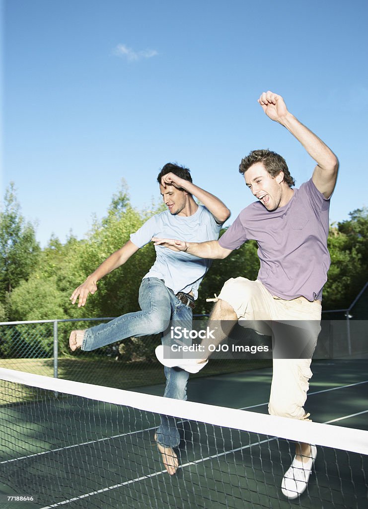 Amici saltando su una rete da tennis - Foto stock royalty-free di Solo uomini