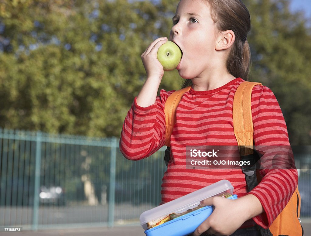 A student outside of school eating  Apple - Fruit Stock Photo