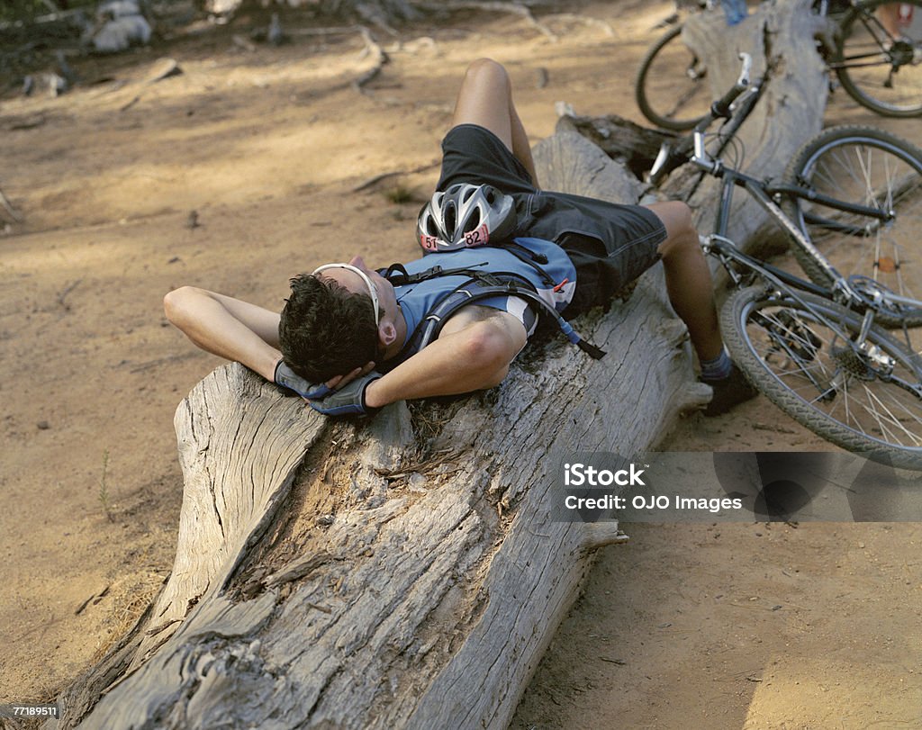 Un ciclista di prendere una pausa in un log - Foto stock royalty-free di 30-34 anni
