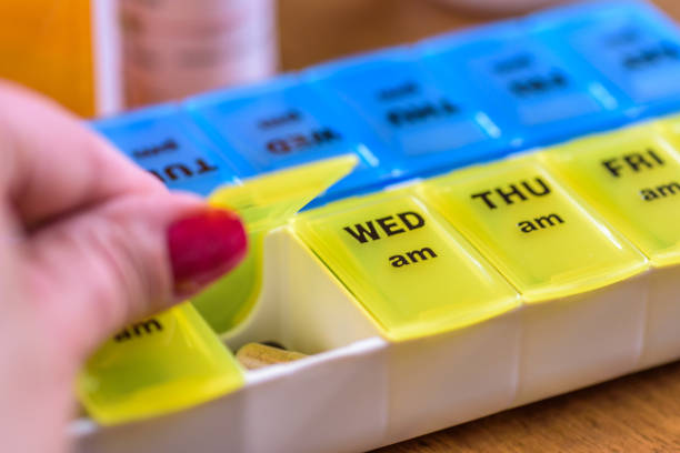istock Cropped Hand Of Woman Taking Pills In Container With Text On Table 773127037