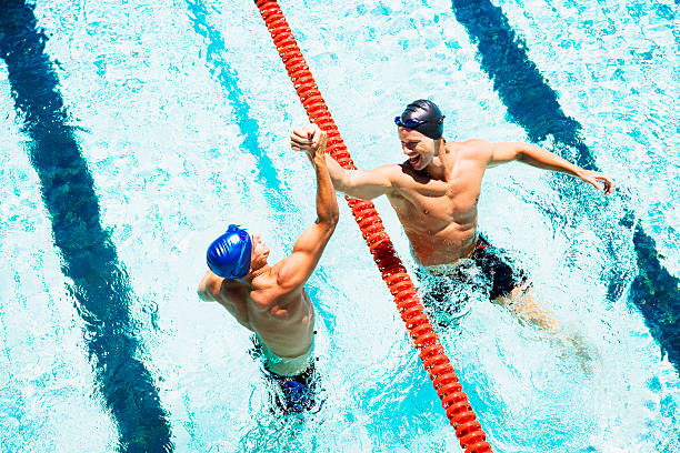 deux longueurs dans une piscine de rejoindre les mains - teamsport photos et images de collection