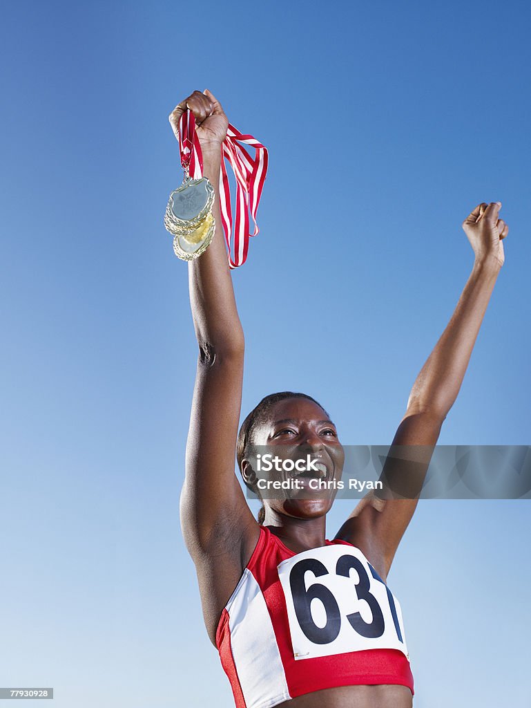 Zwycięski zawodnik trzymać trzech medali nad głową - Zbiór zdjęć royalty-free (Medal)