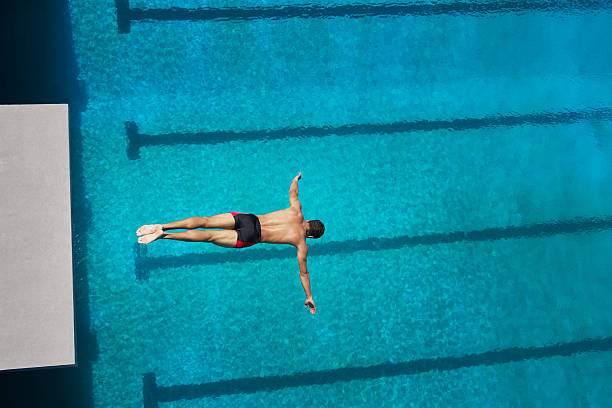 Diver midair going into pool  diving into water stock pictures, royalty-free photos & images