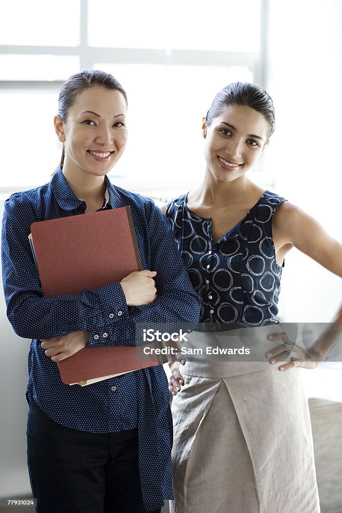 Two businesswomen standing indoors smiling  25-29 Years Stock Photo