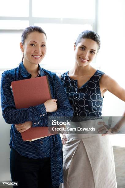 Two Businesswomen Standing Indoors Smiling Stock Photo - Download Image Now - 25-29 Years, Adults Only, Business