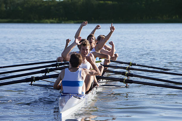 tripulación atletas en una fila de botes aclamando - remar fotografías e imágenes de stock