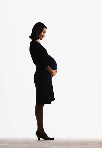 Photo of Woman standing holding her pregnant stomach