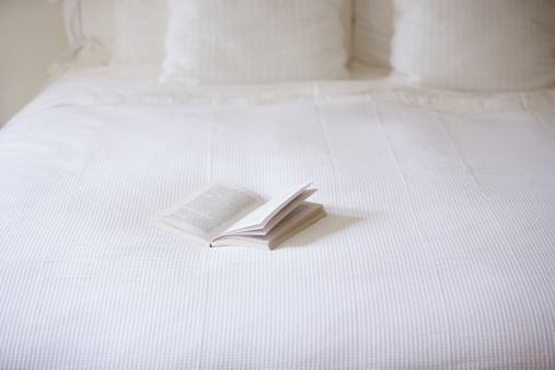 Empty bed with open book on it