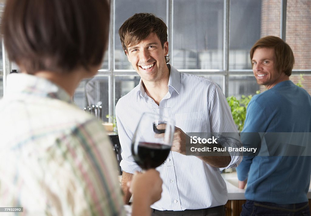 Three people in kitchen with wine  25-29 Years Stock Photo