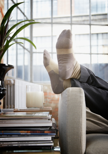 Un hombre pies en alto en el brazo de sofá en casa moderna photo