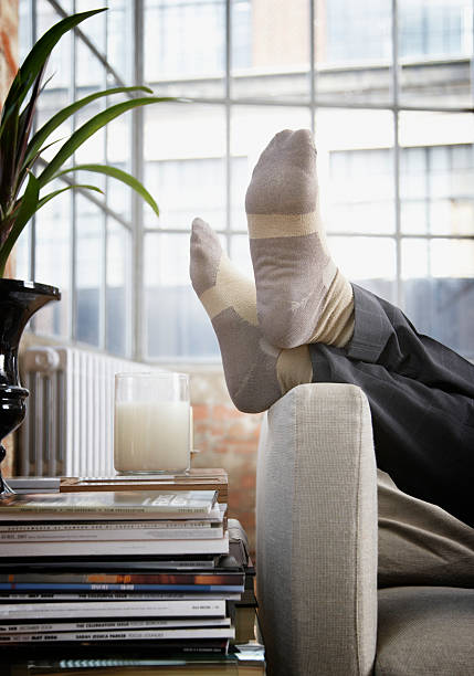 Man's feet up on arm of couch in modern home  legs crossed at ankle stock pictures, royalty-free photos & images