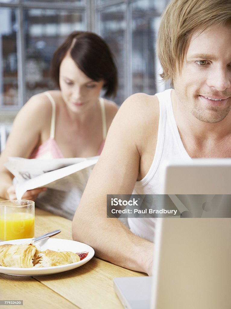 Couple dans la cuisine avec la femme lecture et la - Photo de 25-29 ans libre de droits