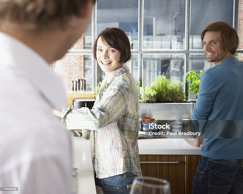 Couple dans la cuisine avec homme debout au premier plan - Photo de 25-29 ans libre de droits