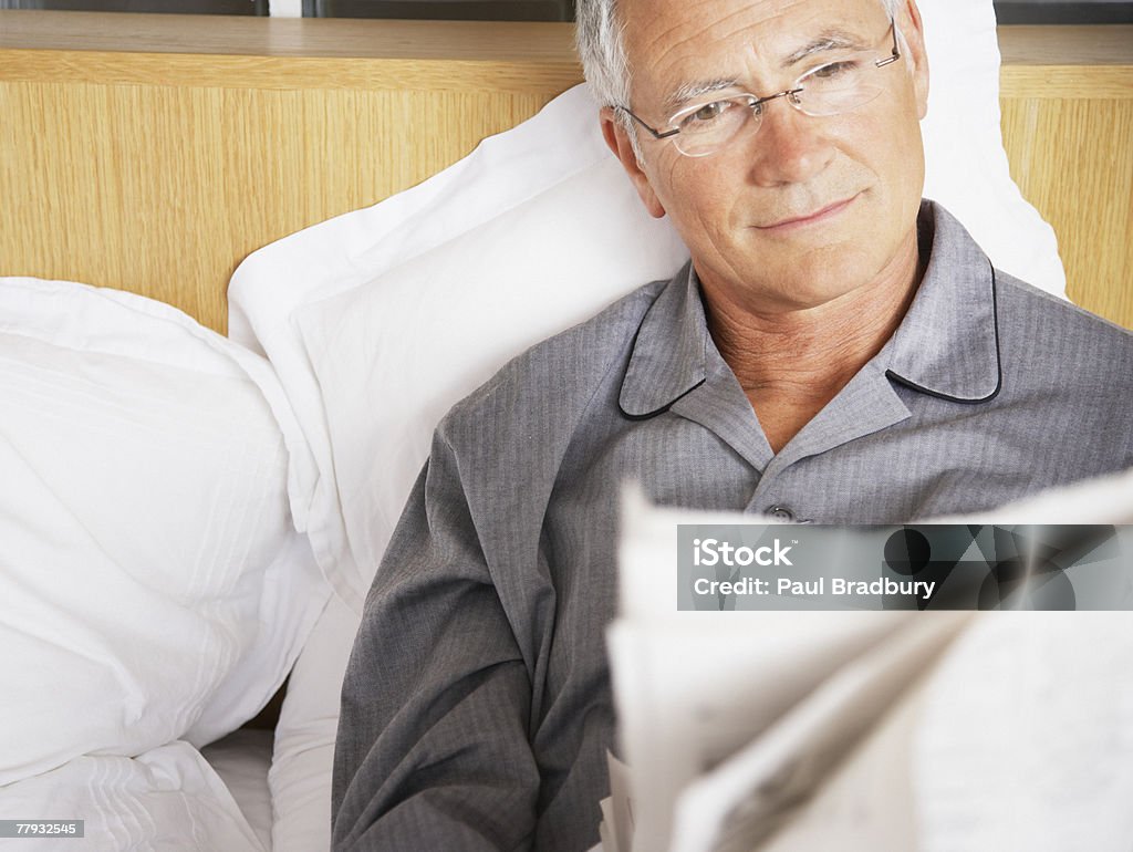 Man reading newspaper in bed  55-59 Years Stock Photo
