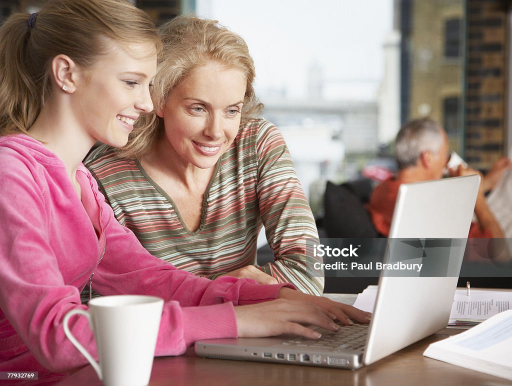 Frau und Mädchen auf laptop mit Mann im Hintergrund - Lizenzfrei 14-15 Jahre Stock-Foto