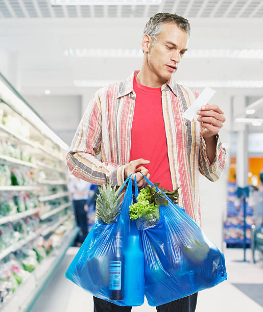 hombre mirando a la lista en supermercado - fruit sale for vegitable fotografías e imágenes de stock