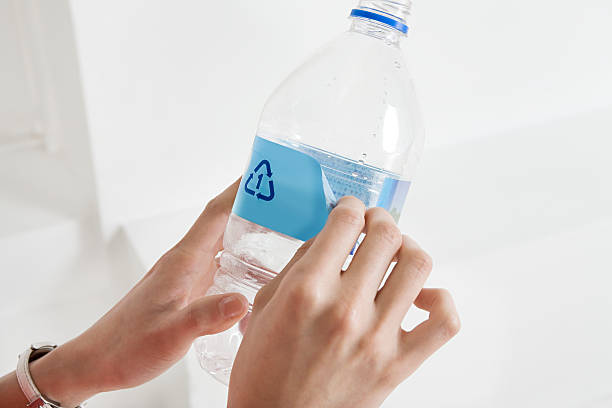 una persona pelar una etiqueta en una botella - bottle plastic label green fotografías e imágenes de stock