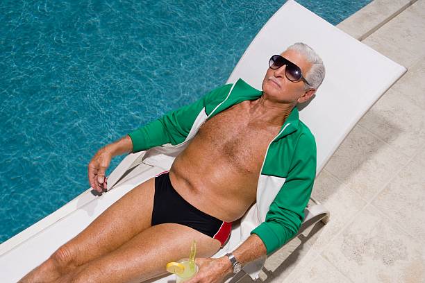 homme senior détente au bord de la piscine - sunbathing photos et images de collection