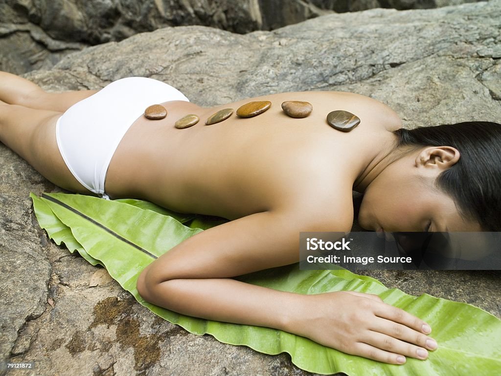 Mujer joven con la terapia de piedras calientes - Foto de stock de Acostado boca abajo libre de derechos