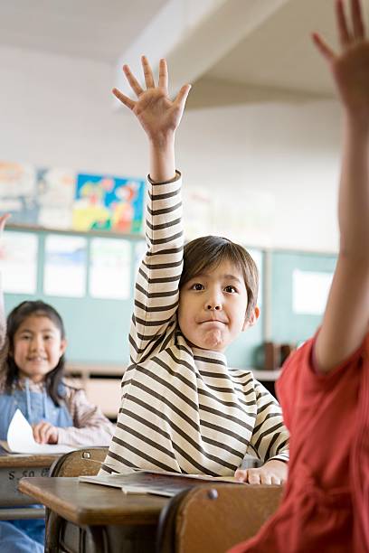 un garçon avec sa lever la main - elementary student little boys classroom child photos et images de collection