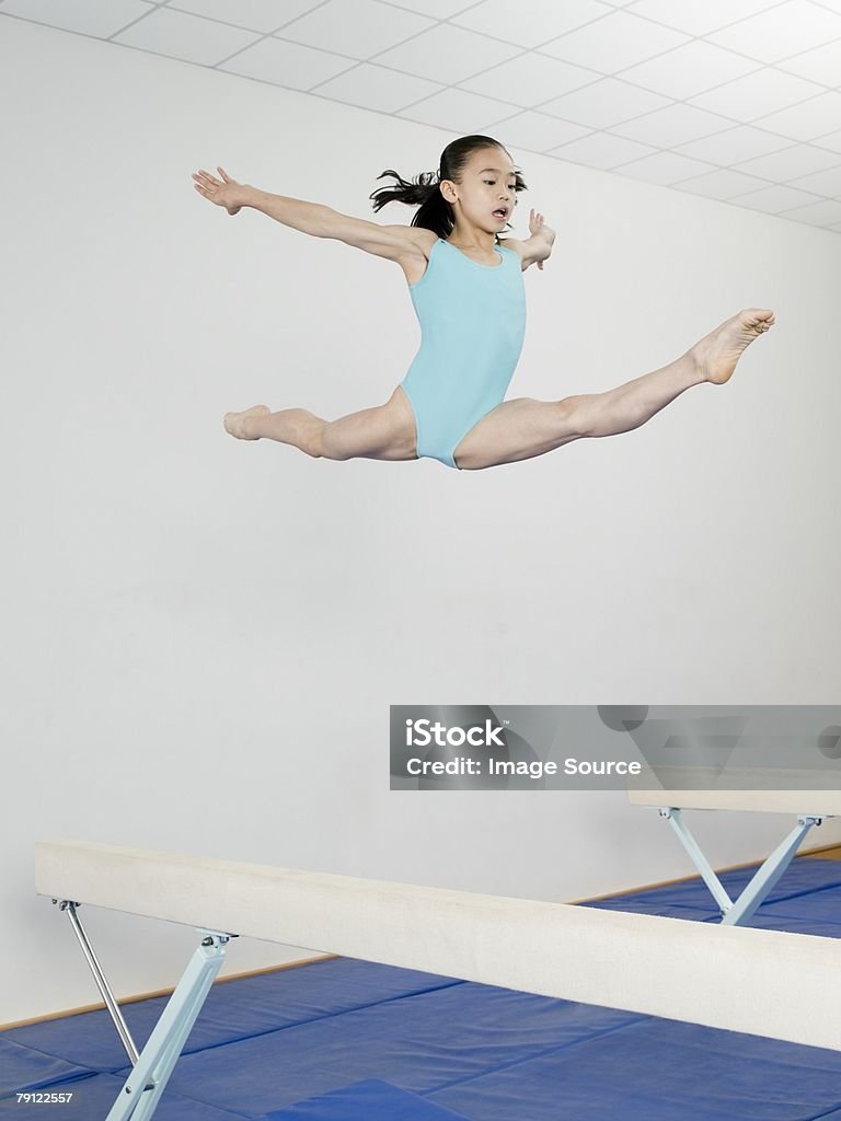 Girl jumping above balance beam  Gymnastics Stock Photo