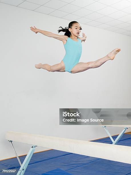 Girl Jumping Above Balance Beam Stock Photo - Download Image Now - Gymnastics, Girls, Jumping