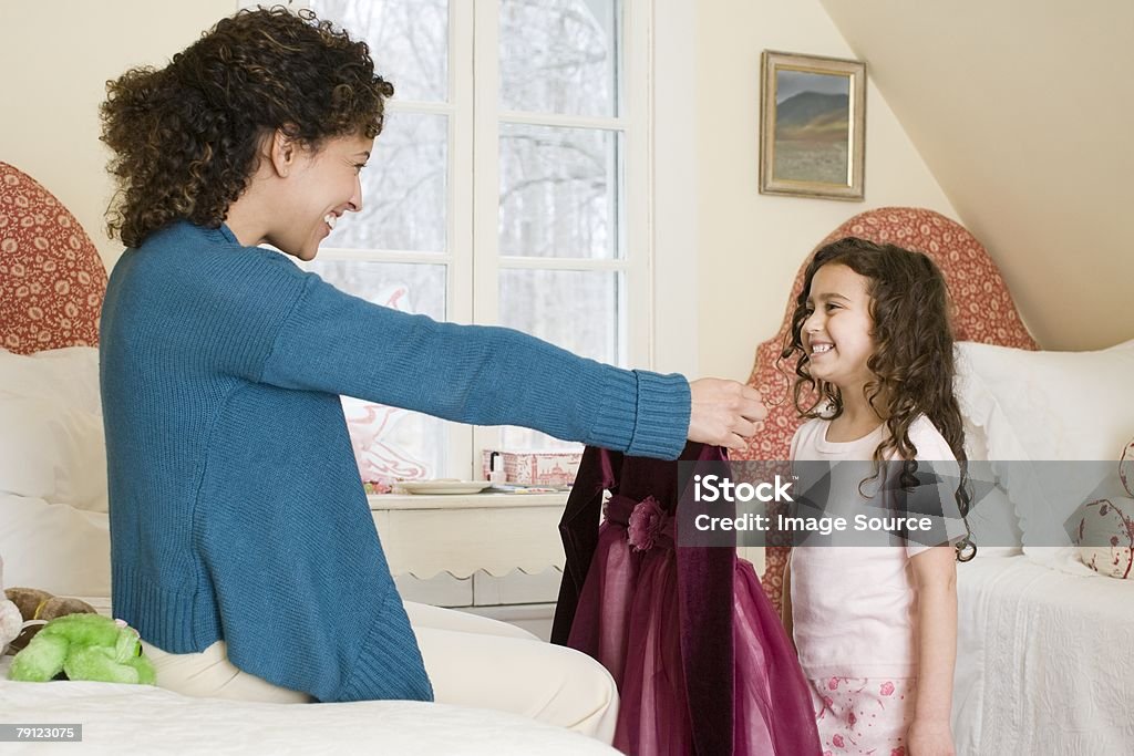 Mother giving dress to daughter  Daughter Stock Photo