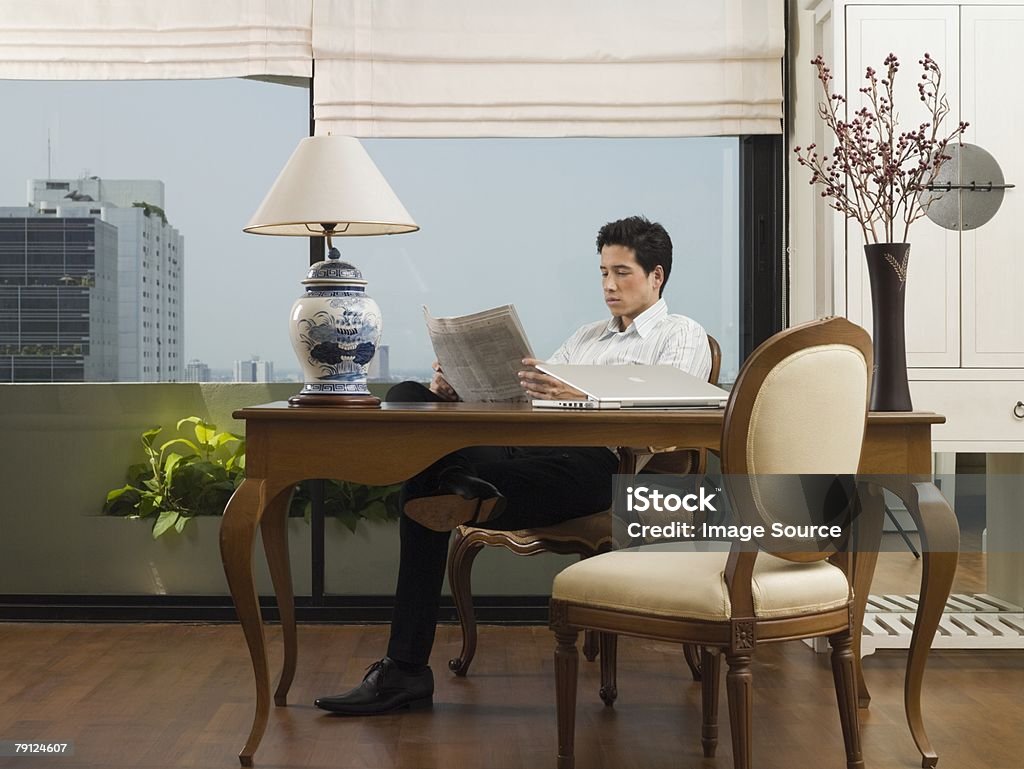 Człowiek czytanie gazety na biurko - Zbiór zdjęć royalty-free (Biuro)
