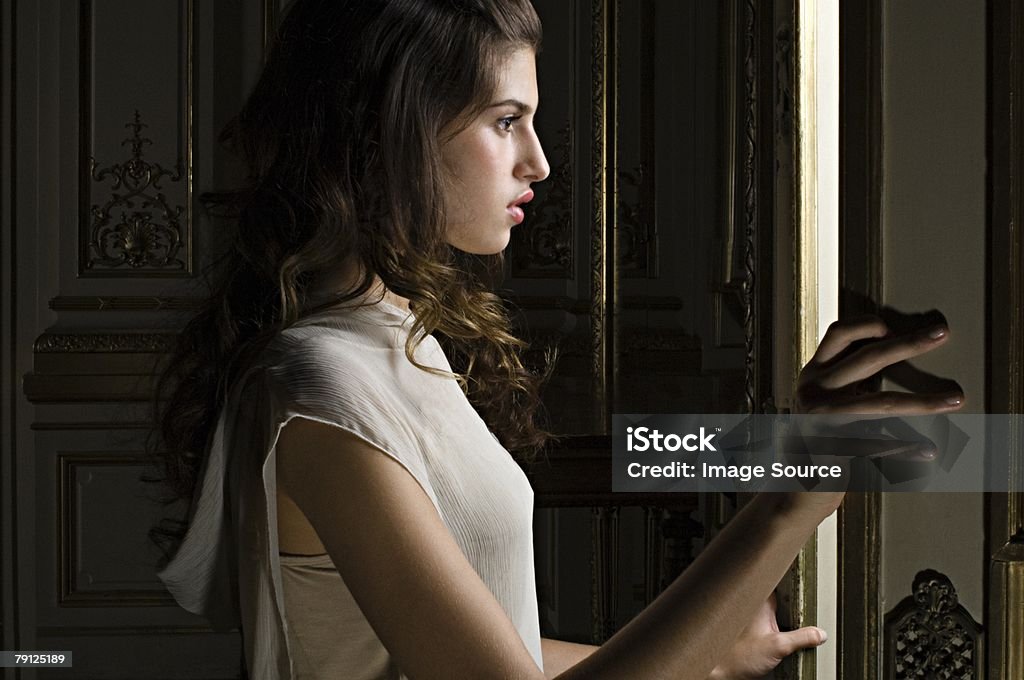 Donna guarda attraverso la porta - Foto stock royalty-free di Mistero