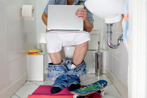 Professional plumber in uniform fixing toilet tank indoors. High quality photo