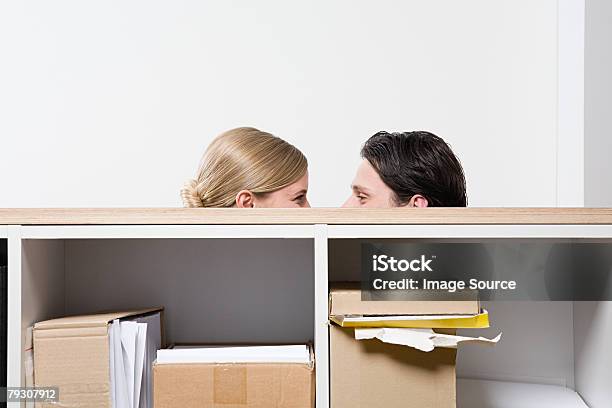 Woman And Man Behind Shelves Stock Photo - Download Image Now - Flirting, Office, Covering