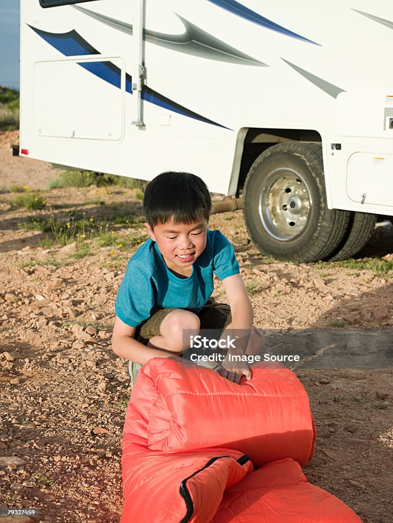 Boy rolling up a sleeping bag  Rolling Stock Photo