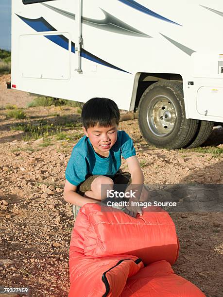 Boy Rolling Up A Sleeping Bag Stock Photo - Download Image Now - Rolling, Sleeping Bag, Adventure