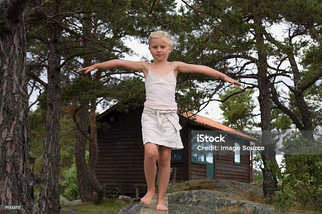 Uma Menina caminhando ao longo de uma tábua de madeira - Foto de stock de Andar royalty-free