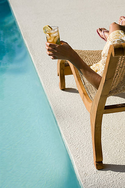 mujer junto a la piscina con una bebida - poolside fotografías e imágenes de stock