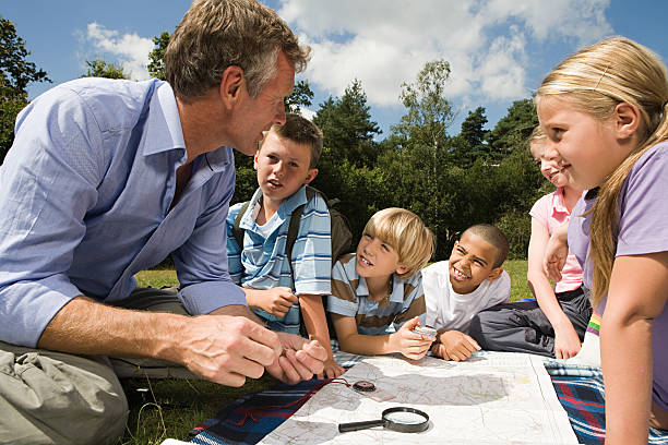 Teacher and pupils with map  orienteering stock pictures, royalty-free photos & images