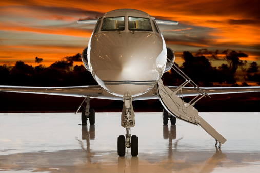 a white business plane takes off against the background of a blue sunny sky