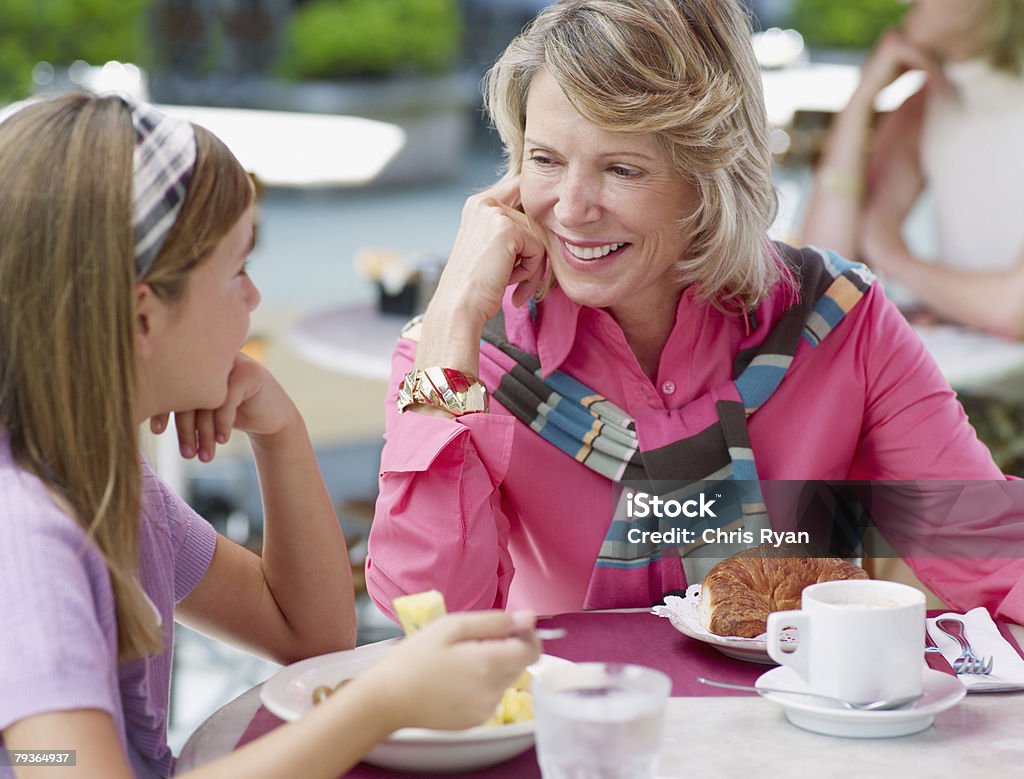 Mulher e jovem garota comendo uma refeição ao ar livre no pátio - Foto de stock de 10-11 Anos royalty-free