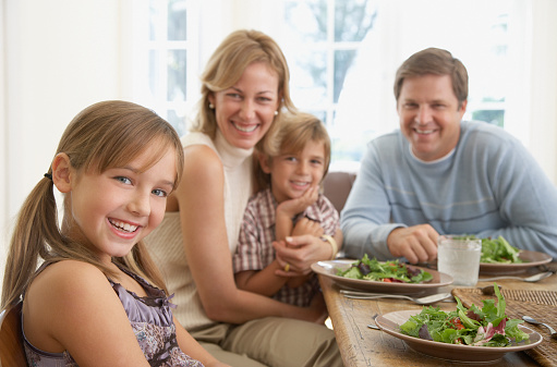 Little girl is having dinner with her family, the mom and dad are sitting down and a girl is kissing her grandmother