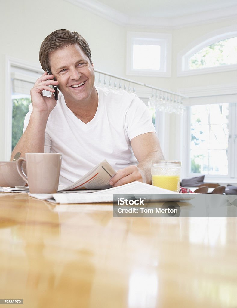 Homme dans la cuisine à l'aide de son téléphone mobile - Photo de Table pour dîner libre de droits