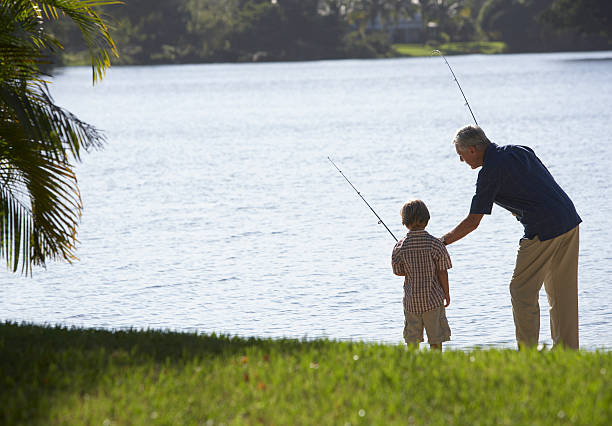 homem e jovem rapaz ao ar livre no parque pesca em um lago - fishing active seniors family senior adult - fotografias e filmes do acervo