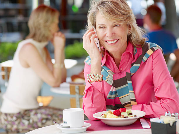 femme sur un patio extérieur avec son téléphone mobile et des fruits frais - connection usa coffee cup mug photos et images de collection