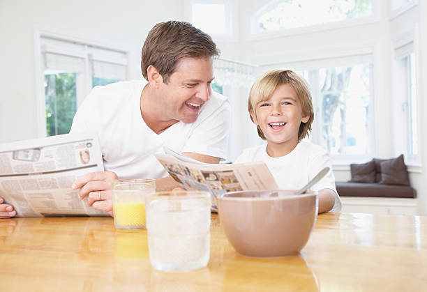 homme et jeune garçon de rire en lisant un journal et cuisine - connection usa coffee cup mug photos et images de collection