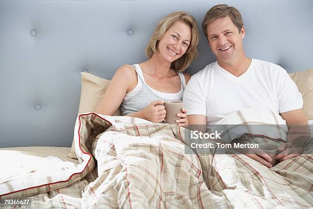 Paar Sitzen Im Bett Mit Tassen Stockfoto und mehr Bilder von 40-44 Jahre - 40-44 Jahre, Anfang, Bett