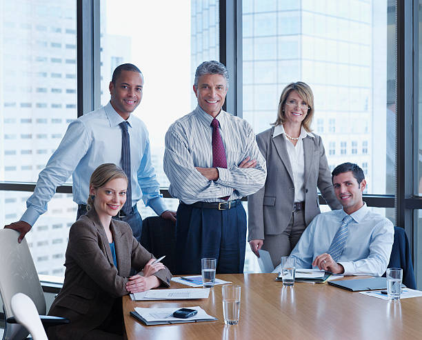 Five businesspeople in a boardroom looking at camera  five people stock pictures, royalty-free photos & images