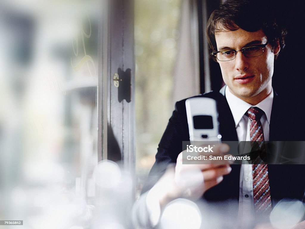 Бизнесмен в ресторане глядя на его Мобильный телефон - Стоковые фото 25-29 лет роялти-фри