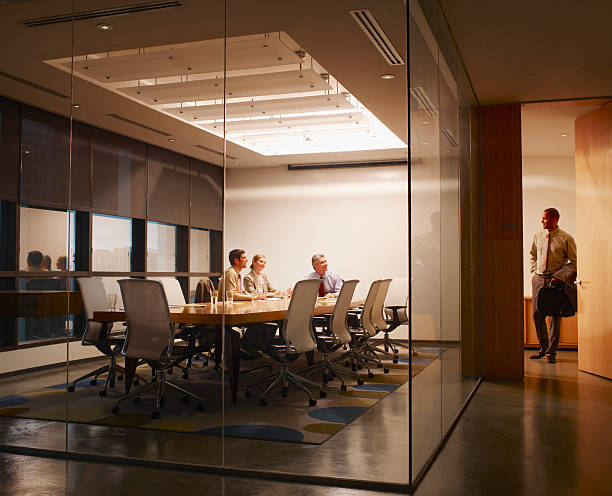 Three businesspeople in boardroom watching businessman leave  office leave stock pictures, royalty-free photos & images